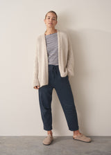 Woman wearing oversized chunky cardigan in oatmeal with dark grey blue joggers and stripe knit top