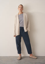 Woman wearing oversized chunky cardigan in oatmeal with dark grey blue joggers and stripe knit top