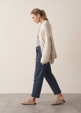 Woman wearing oversized chunky cardigan in oatmeal with dark grey blue joggers and stripe knit top