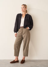 A woman wearing a vintage white long-sleeve button-up sheer blouse and light green khaki trousers.