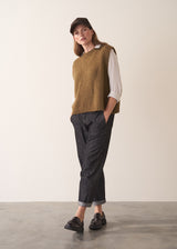 Woman wearing a white silk shirt and dark jeans against a plain background