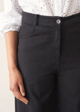 Woman wearing white broderie anglaise top and black cotton wide leg trousers with sandals