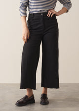 Woman wearing striped sweater and black wide leg cropped trousers