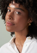 Woman wearing double hoop gold earrings with white shirt