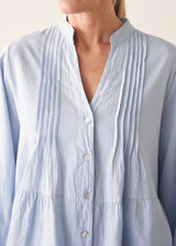 Woman wearing blue pintuck shirt with beige linen trousers