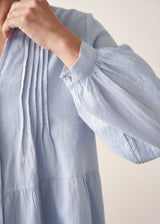 Woman wearing blue pintuck shirt with beige linen trousers