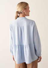 Woman wearing blue pintuck shirt with beige linen trousers