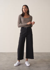 Woman wearing cashmere-blend long sleeve stripe top and black wide leg cropped trousers.