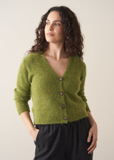 Woman wearing a green marled v-neck cardigan with a white top and black trousers