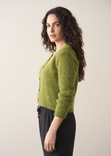 Woman wearing a green marled v-neck cardigan with a white top and black trousers