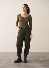 Woman wearing a khaki green top and dark green barrel leg trousers