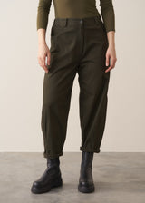 Woman wearing a khaki green top and dark green barrel leg trousers