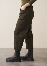 Woman wearing a khaki green top and dark green barrel leg trousers