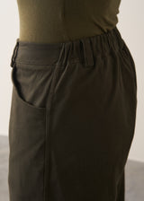 Woman wearing a khaki green top and dark green barrel leg trousers