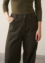 Woman wearing a khaki green top and dark green barrel leg trousers