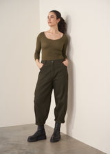 Woman wearing a khaki green top and dark green barrel leg trousers