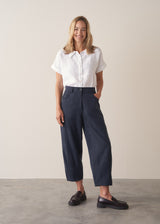 Woman wearing a white cropped linen shirt and navy barrel leg trousers