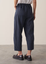 Woman wearing a white cropped linen shirt and navy barrel leg trousers