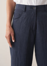 Woman wearing a white cropped linen shirt and navy barrel leg trousers