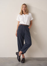 Woman wearing a white cropped linen shirt and navy barrel leg trousers