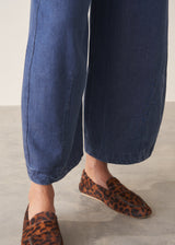 A woman wearing a white long-sleeve embroidered blouse and blue wide-leg cargo trousers, paired with brown loafers.