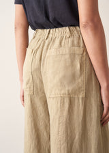 A woman wearing like green linen wide leg cargo trousers and a black t-shirt