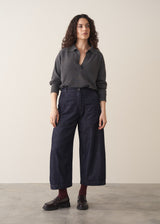 Woman wearing a grey sweater and dark blue wide leg cargo jeans with brown loafers