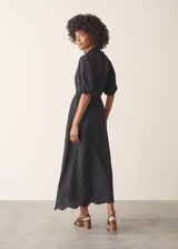 Woman wearing a 3/4 sleeve black maxi broderie dress with scalloped hem against a beige background