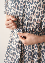 Woman wearing grey leopard print dress and nude sandals