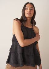 Woman wearing black layered halter top with brown linen trousers