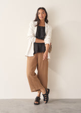 Woman wearing black layered halter top with brown linen trousers