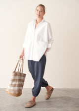 A woman wearing a large white smock shirt with navy blue trousers