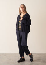 A woman wearing a dark navy light cardigan with navy satin trousers