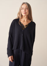 A woman wearing a dark navy light cardigan with navy satin trousers