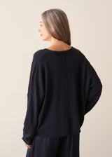 A woman wearing a dark navy light cardigan with navy satin trousers