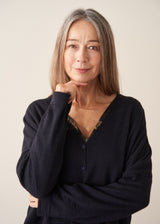 A woman wearing a dark navy light cardigan with navy satin trousers