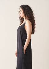 Woman wearing a black sleeveless dress against a plain background
