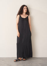 Woman wearing a black sleeveless dress against a plain background