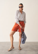 Woman wearing striped shirt and red linen shorts with sandals
