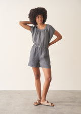 Woman wearing a checked linen top and matching checked linen shorts against a plain background