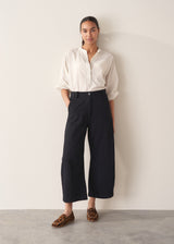 Woman wearing a white shirt and a pair of cropped black barrel-leg denim jeans