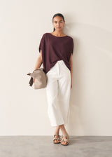 Woman wearing white cropped barrel leg jeans with plum short sleeve top