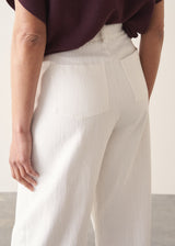 Woman wearing white cropped barrel leg jeans with plum short sleeve top