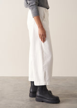 Person wearing grey cardigan and white denim barrel leg jeans