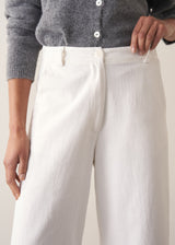 Person wearing grey cardigan and white denim barrel leg jeans