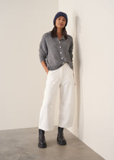 Person wearing grey cardigan and white denim barrel leg jeans
