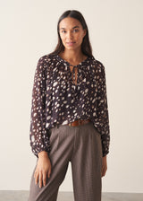 A woman wearing a dark brown deer print blouse with checked trousers and a dark grey blazer