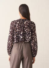 A woman wearing a dark brown deer print blouse with checked trousers and a dark grey blazer