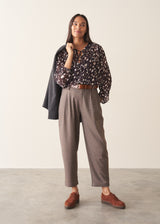 A woman wearing a dark brown deer print blouse with checked trousers and a dark grey blazer