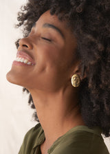 Woman wearing large gold hammered stud earrings